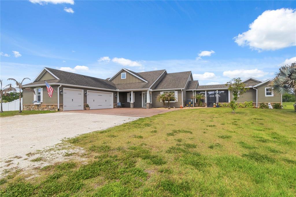A single-story house with a two-car garage, stone accents, and a large front lawn — 4901 MANOR HOUSE LANE, ST CLOUD, FL