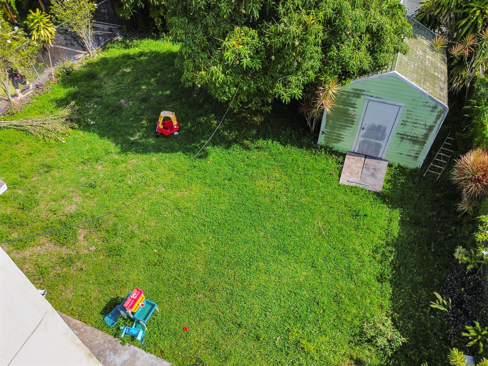 An aerial view of a grassy backyard featuring a shed, a tree, and children's toys — 7337 SW 21st Street, Miami FL 33155, MIAMI, FL