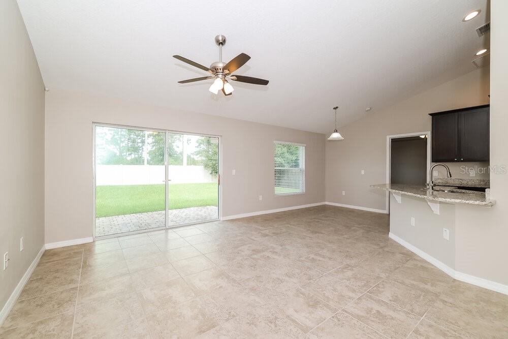 An open-concept living area features tile flooring, a ceiling fan, and sliding glass patio doors — 3042 DREMA DRIVE, ST CLOUD, FL