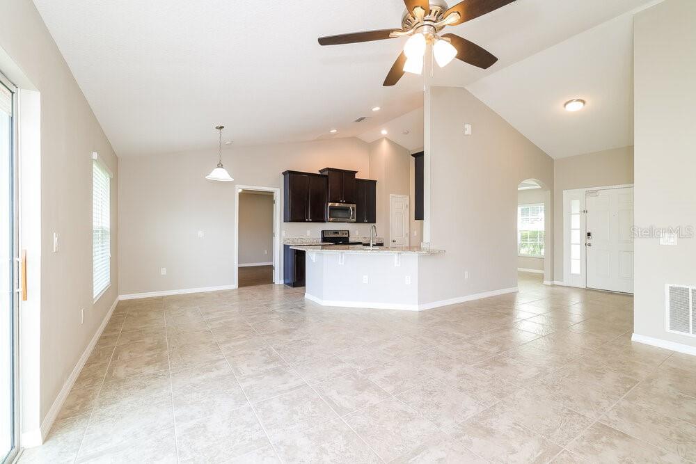 An open-concept kitchen and living area with tile flooring, dark cabinetry, and vaulted ceilings — 3042 DREMA DRIVE, ST CLOUD, FL