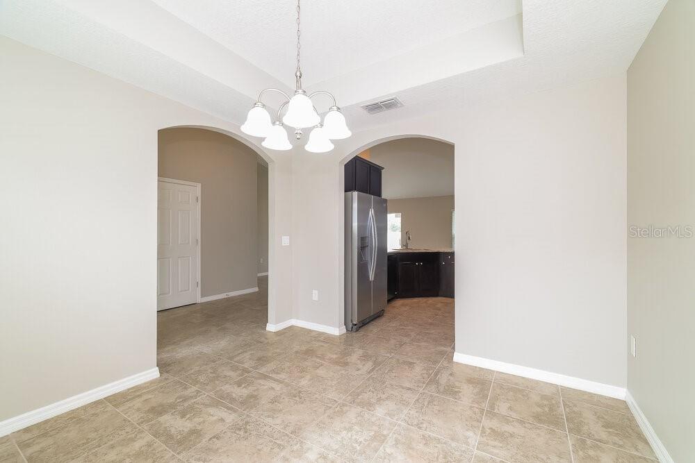 A dining area with tile flooring and a chandelier leads into a kitchen with appliances — 3042 DREMA DRIVE, ST CLOUD, FL