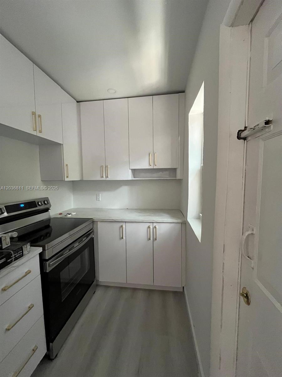 A small kitchen features white cabinets, a stainless steel stove, and light-colored countertops — 602 SW 13th Ave # 4, Miami FL 33135, MIAMI, FL