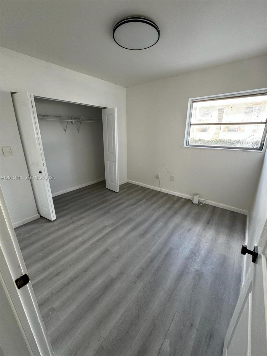 A bedroom features gray wood-look flooring, white walls, a closet, and a single window — 602 SW 13th Ave # 4, Miami FL 33135, MIAMI, FL