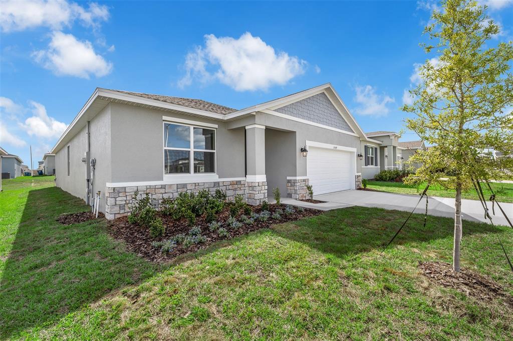 A single-story house with a gray stucco exterior, stone veneer accents, and a two-car garage — 6747 WINTERBERRY DRIVE, LAKE HAMILTON, FL