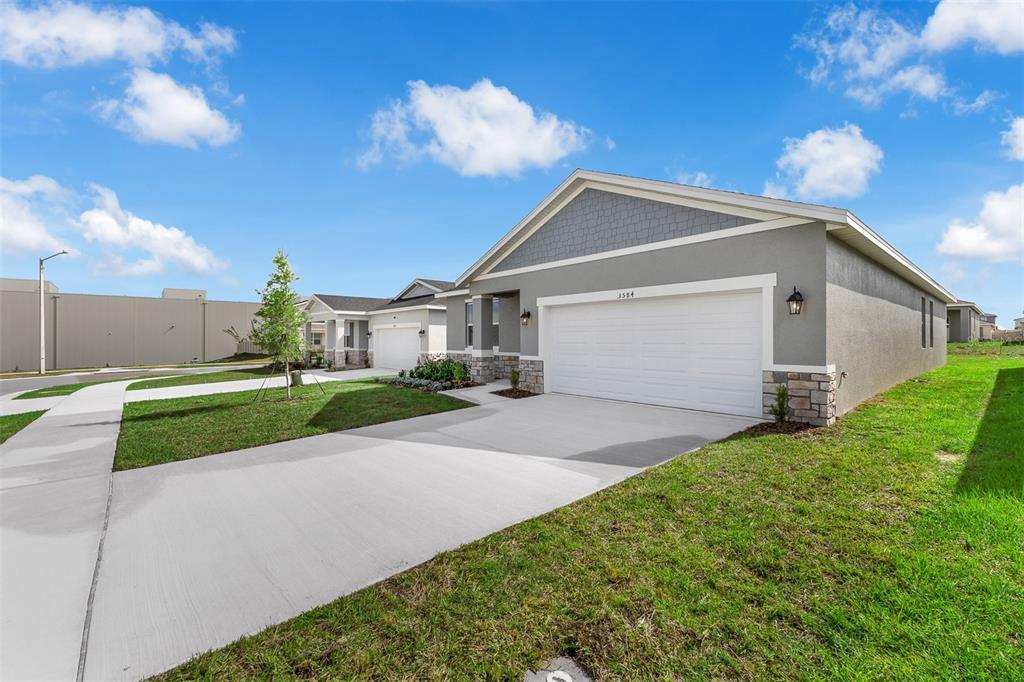A gray single-story house with a two-car garage and stone accents sits on a lawn — 6747 WINTERBERRY DRIVE, LAKE HAMILTON, FL