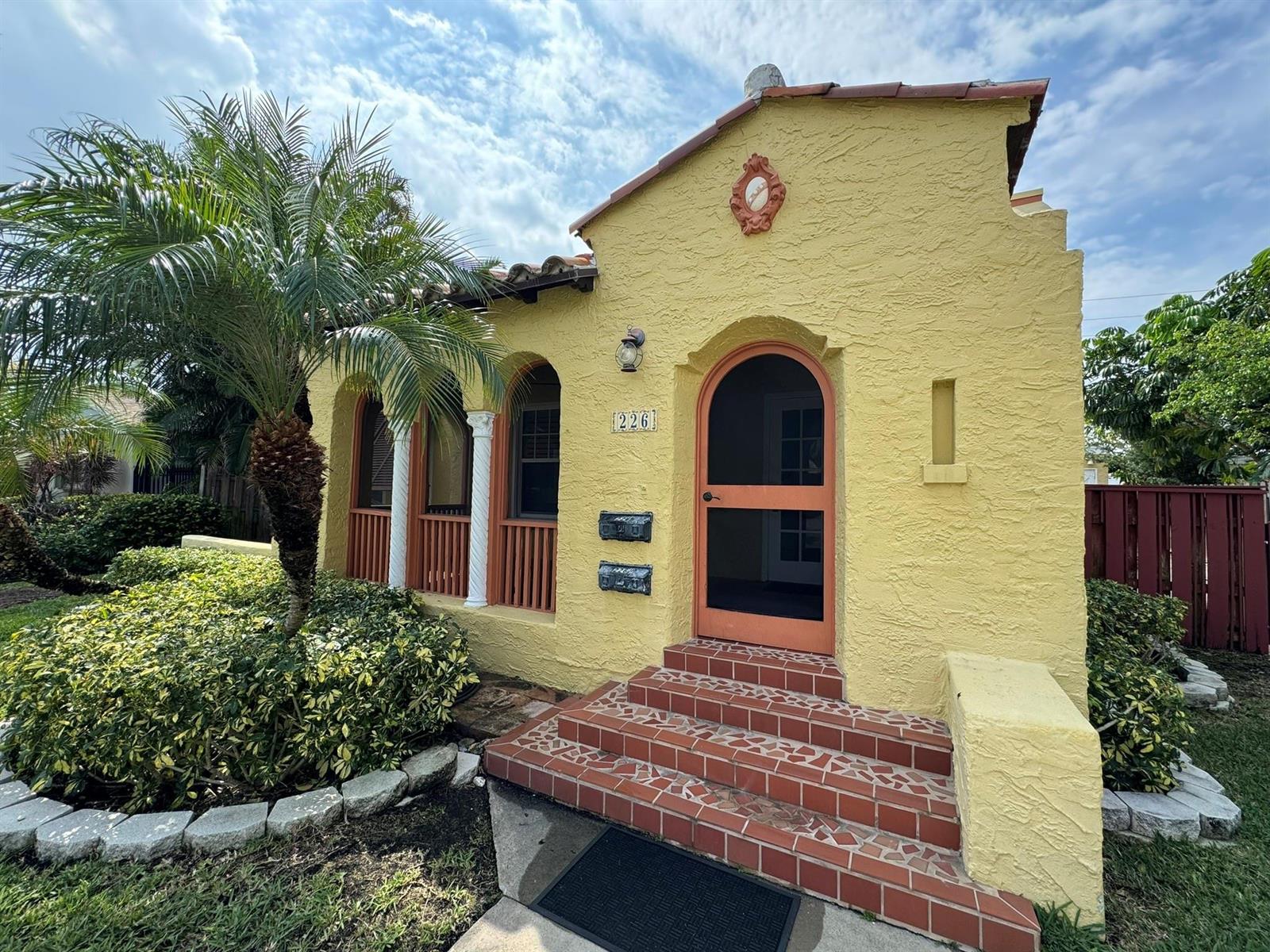 A yellow stucco house features an arched front door, tiled steps, and a small palm tree — 226 NE 7th, Delray Beach FL 33483, DELRAY BEACH, FL