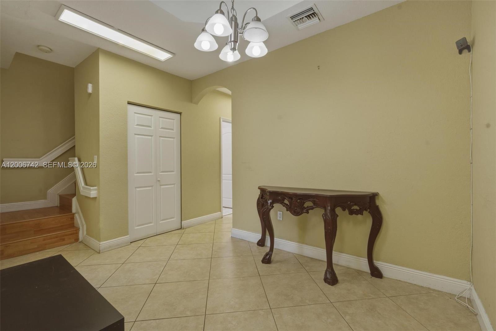 A foyer features tile flooring, a wooden console table, a chandelier, and a staircase — 16613 NW 71st Ave, Miami Lakes FL 33014, MIAMI LAKES, FL