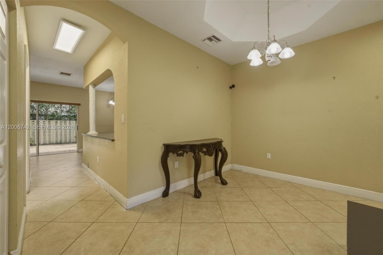 This dining area features beige walls, tile flooring, a chandelier, and a decorative console table — 16613 NW 71st Ave, Miami Lakes FL 33014, MIAMI LAKES, FL