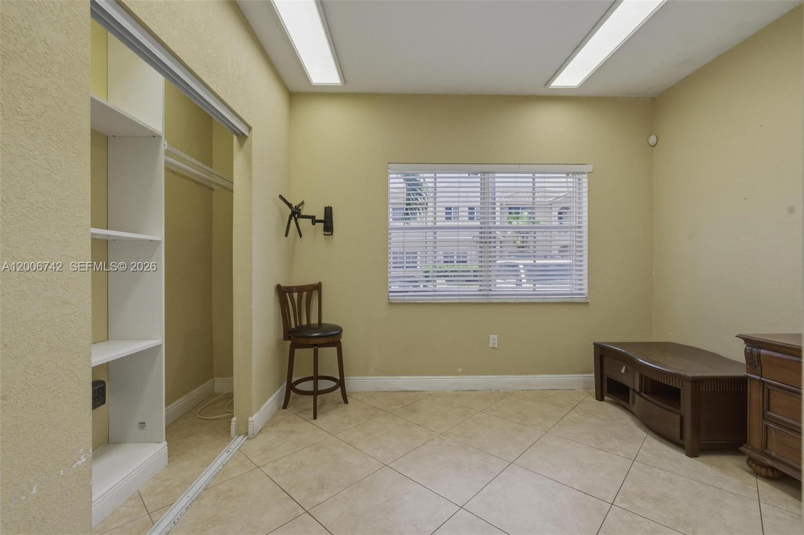 A room with beige walls, tile flooring, a window with blinds, and a built-in closet — 16613 NW 71st Ave, Miami Lakes FL 33014, MIAMI LAKES, FL