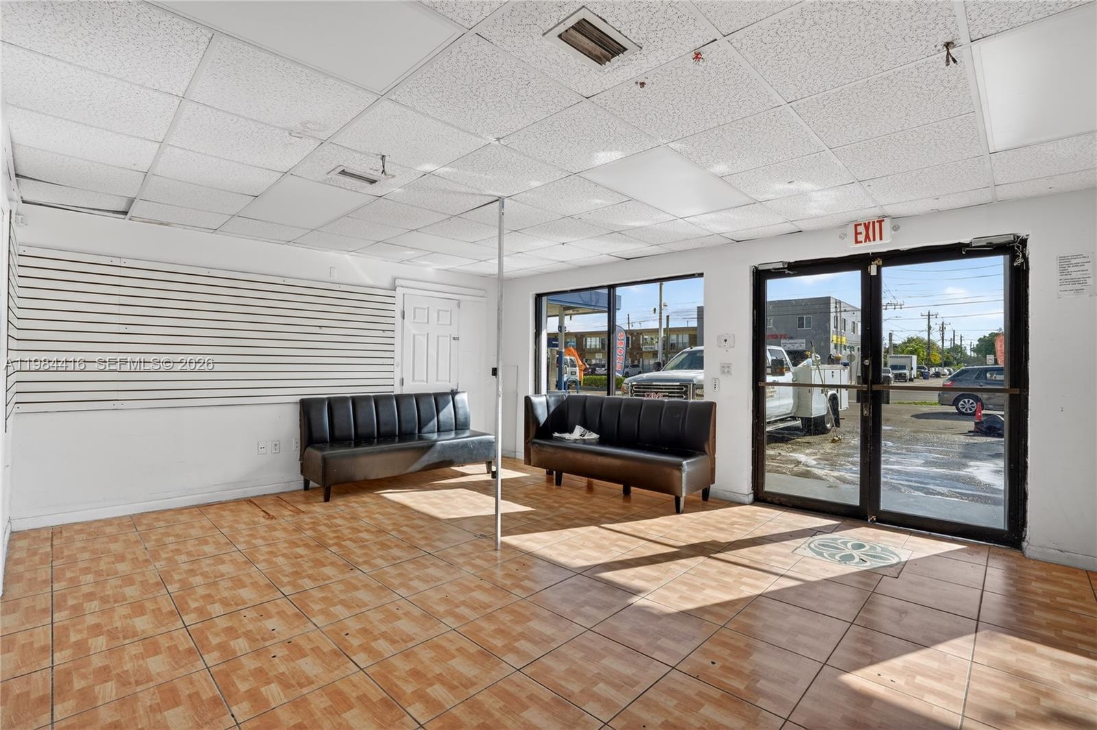 A commercial room features tiled flooring, two black sofas, slat wall panels, and glass doors — 200 SW 57th AVE, FL 33144, FL