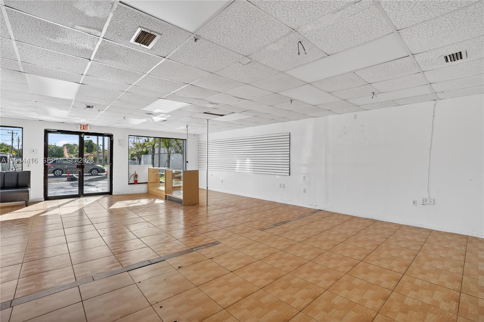 An empty commercial space features a drop ceiling, tiled flooring, and a glass storefront entrance — 200 SW 57th AVE, FL 33144, FL