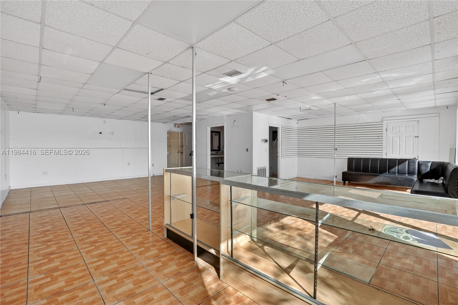 A commercial space features tiled flooring, a drop ceiling, glass display cases, and a sofa — 200 SW 57th AVE, FL 33144, FL
