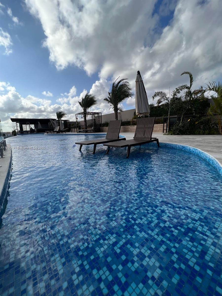 Two lounge chairs sit inside a shallow swimming pool with a tiled bottom and palm trees — Menesse Tulum C. Asteroide, Tulum Centro # 329, QR, QR