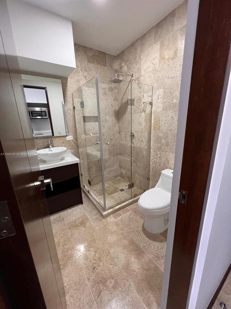 A bathroom features a glass-enclosed shower, a white pedestal sink, and tan stone tile flooring — Menesse Tulum C. Asteroide, Tulum Centro # 329, QR, QR