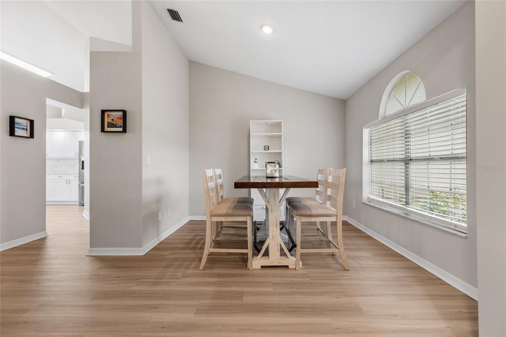 A dining area features light wood-look flooring, a wooden table with four chairs, and a window — 22861 STERLING MANOR LOOP, LUTZ, FL