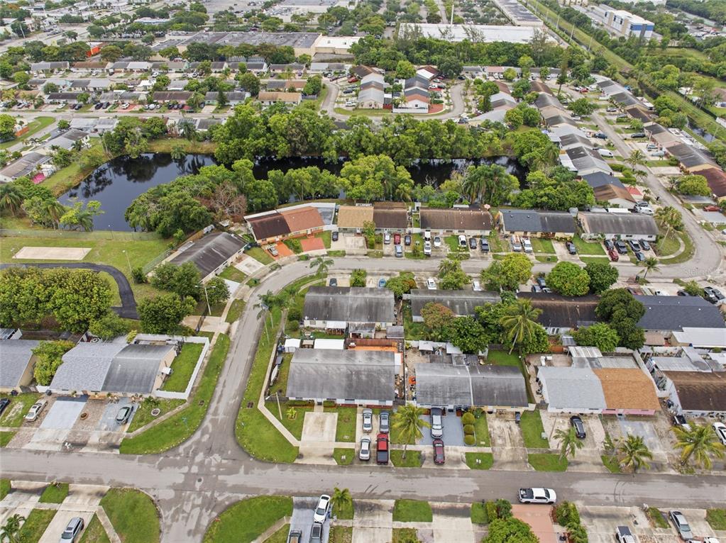 An aerial view shows a residential neighborhood with townhomes, a pond, and paved streets — 4908 PIMLICO COURT, WEST PALM BEACH, FL