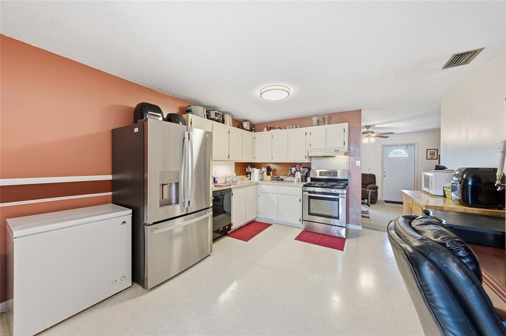 A kitchen with white cabinets, stainless steel appliances, and a chest freezer on the left — 4908 PIMLICO COURT, WEST PALM BEACH, FL