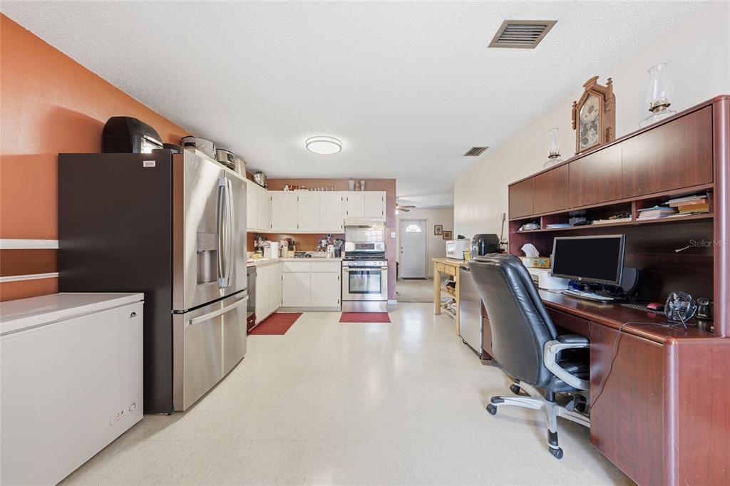 A kitchen with stainless steel appliances, white cabinetry, and an integrated home office desk area — 4908 PIMLICO COURT, WEST PALM BEACH, FL