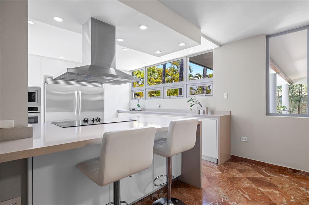 A modern kitchen features a large island, stainless steel appliances, and marble-patterned tile flooring — 69 ROBLE, GUAYNABO, PR