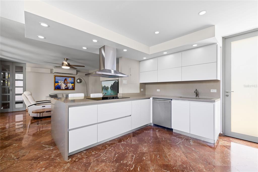 A modern kitchen features white flat-panel cabinets, a stainless steel range hood, and marble flooring — 69 ROBLE, GUAYNABO, PR