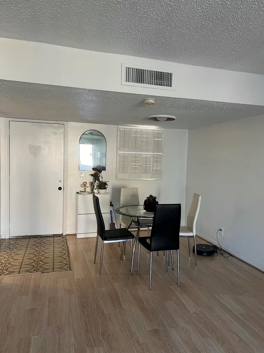 A dining area features a glass table, four chairs, a white cabinet, and light wood flooring — 719 Lori Drive # 203, Palm Springs FL 33461, PALM SPRINGS, FL