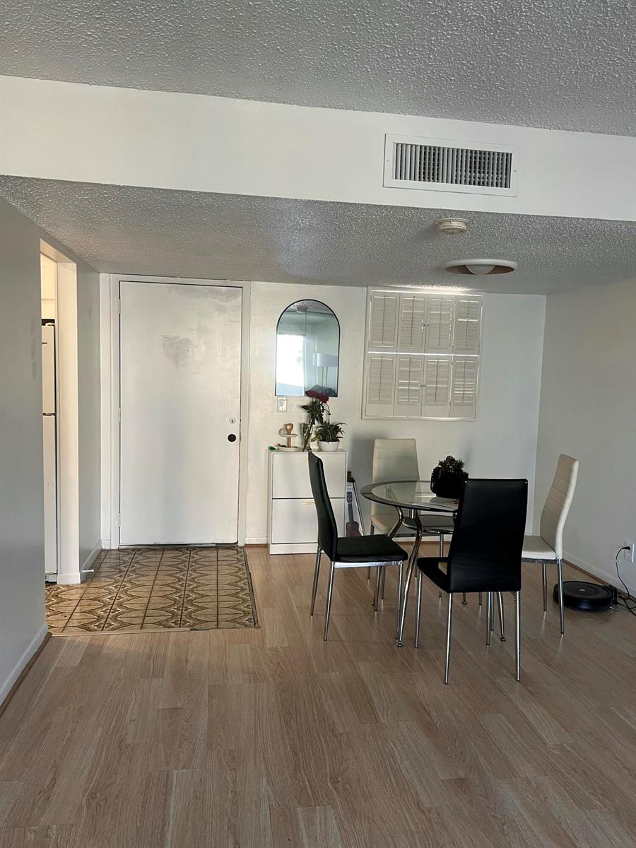 A dining area features a glass table, four chairs, a white cabinet, and light wood flooring — 719 Lori Drive # 203, Palm Springs FL 33461, PALM SPRINGS, FL