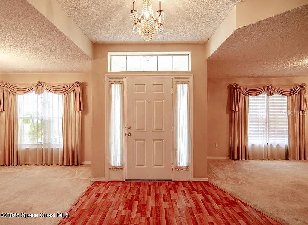 An entryway features a white front door, a crystal chandelier, and wood-look flooring — 778 NW HAMM STREET, PALM BAY, FL