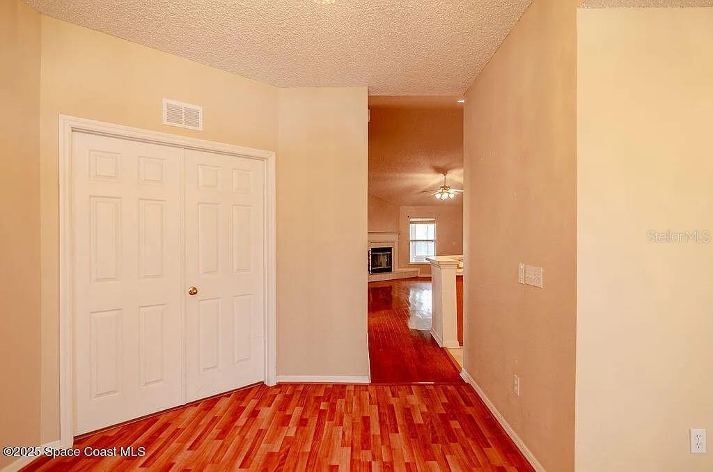 A hallway with wood flooring leads to a living area featuring a fireplace — 778 NW HAMM STREET, PALM BAY, FL