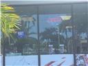 A view through a glass storefront window showing palm trees and a blue sign — 5418 W Atlantic Boulevard, Margate FL 33063, MARGATE, FL