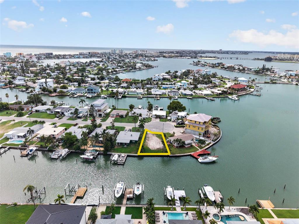 An aerial view shows a vacant waterfront lot outlined in yellow on a residential peninsula — 643 NORMANDY ROAD, MADEIRA BEACH, FL