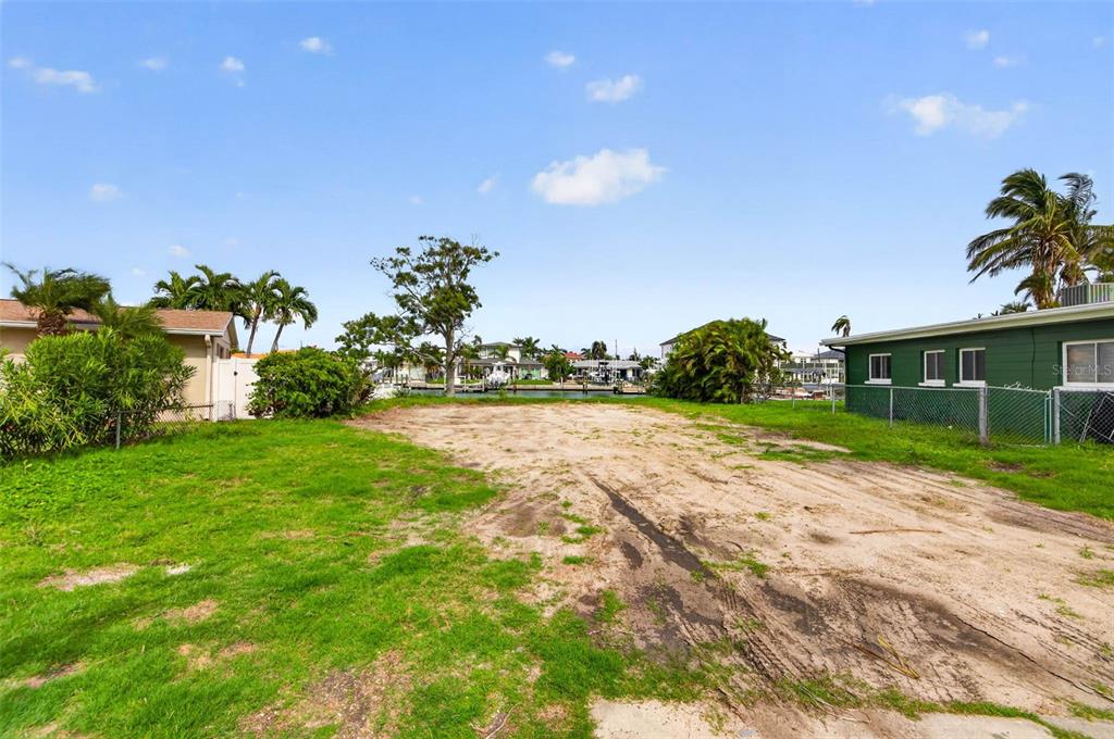 A vacant, grassy lot sits between two houses with a view of a canal — 643 NORMANDY ROAD, MADEIRA BEACH, FL