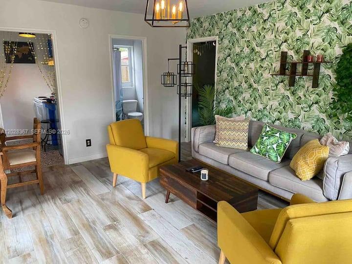 A living room features a gray sofa, yellow armchairs, and a tropical-patterned accent wall — 1516 S 17th Ave # 1516, Hollywood FL 33020, HOLLYWOOD, FL