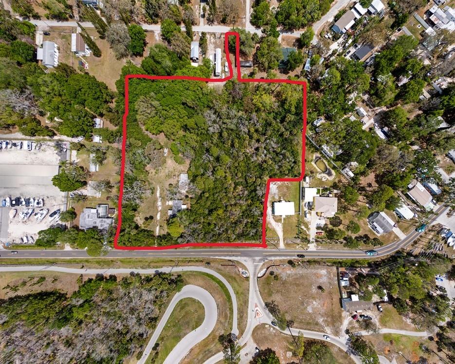 An aerial view shows a large, wooded, rectangular lot outlined in red near a road — 1204 BAILLIES BLUFF ROAD, HOLIDAY, FL