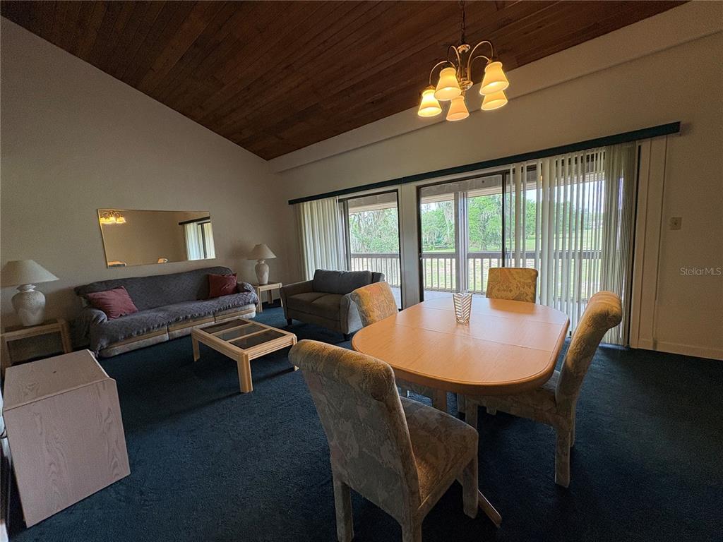A living and dining area features a wood-paneled vaulted ceiling and sliding glass doors — 167 PALM VIEW COURT UNIT 3487, HAINES CITY, FL