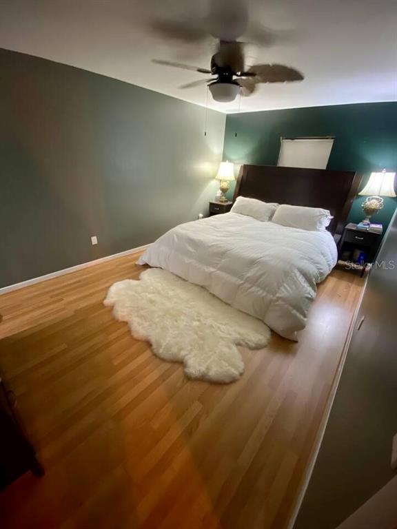 A bedroom features a bed with a white comforter, a faux fur rug, and hardwood floors — 6338 51ST AVENUE N UNIT 0, ST PETERSBURG, FL