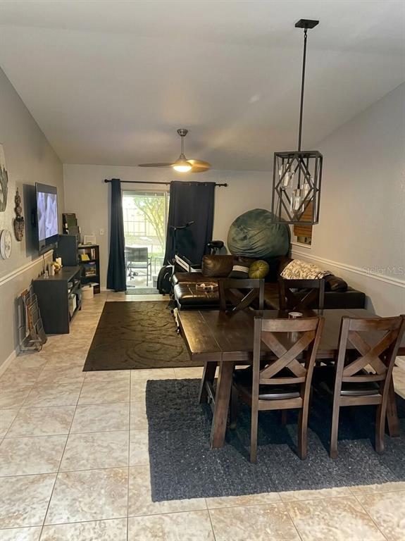 This open-concept living and dining area features tile flooring, a ceiling fan, and sliding doors — 6338 51ST AVENUE N UNIT 0, ST PETERSBURG, FL