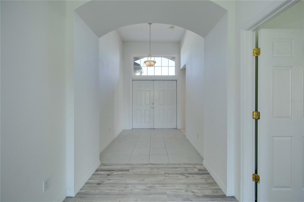 An entryway features a vaulted ceiling, tile flooring, and a white double-door front entrance — 1679 PINYON PINE DRIVE, SARASOTA, FL