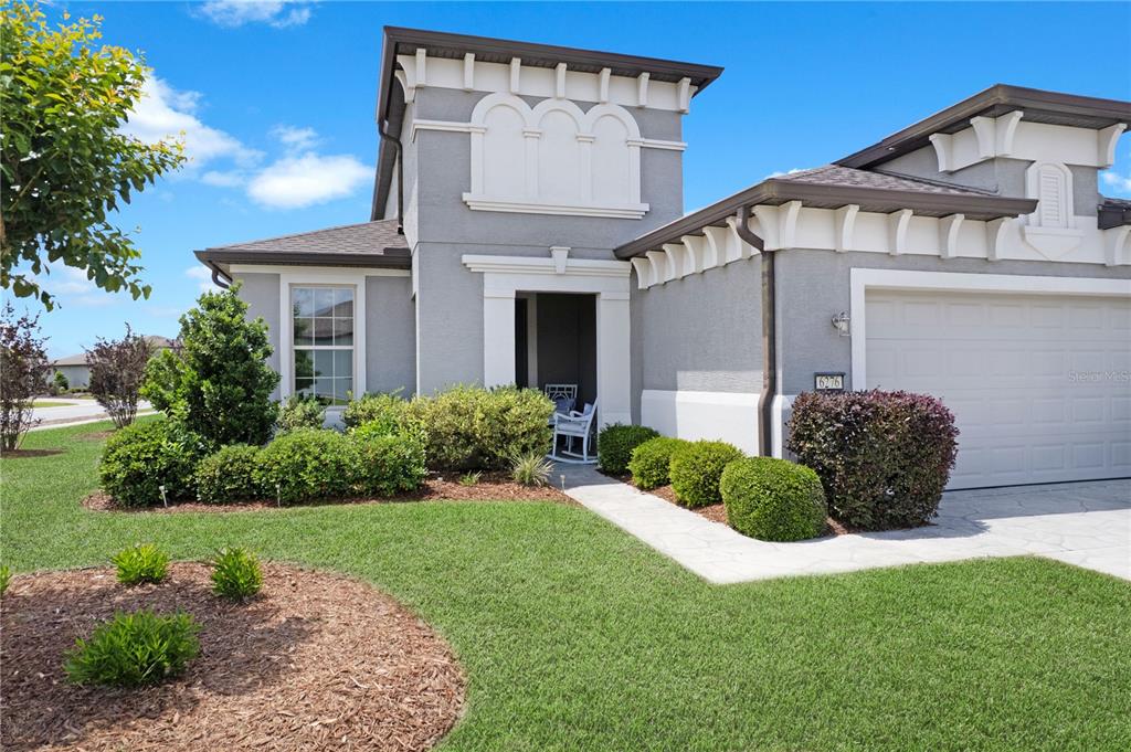 A gray single-story house features a white-trimmed entryway, a two-car garage, and landscaped front yard — 6276 SW 93RD TERRACE, OCALA, FL