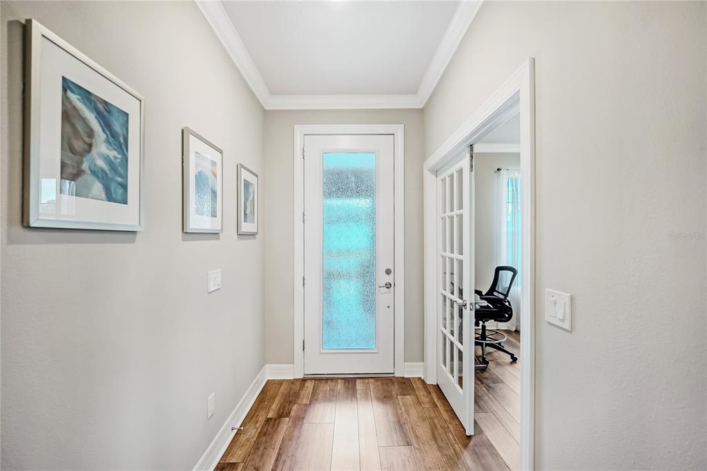 A bright entryway features wood-look flooring, a frosted glass front door, and a French-door office — 6276 SW 93RD TERRACE, OCALA, FL