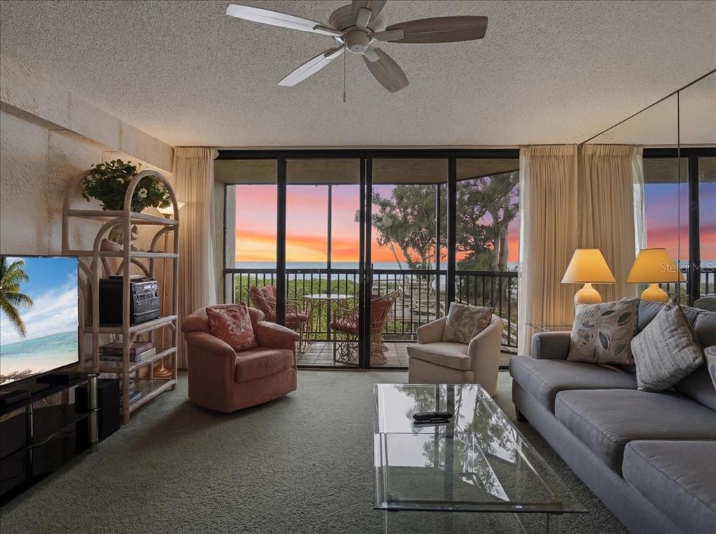 A living room with a glass coffee table, gray sofa, and a balcony overlooking the ocean — 5611 GULF OF MEXICO DRIVE UNIT 3, LONGBOAT KEY, FL
