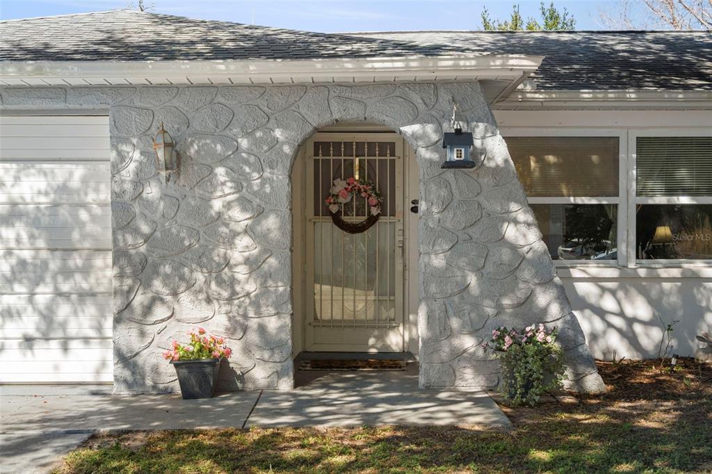 The exterior of a house features a stone-textured facade, an arched entryway, and a security door — 6333 ABERDEEN AVENUE, NEW PORT RICHEY, FL