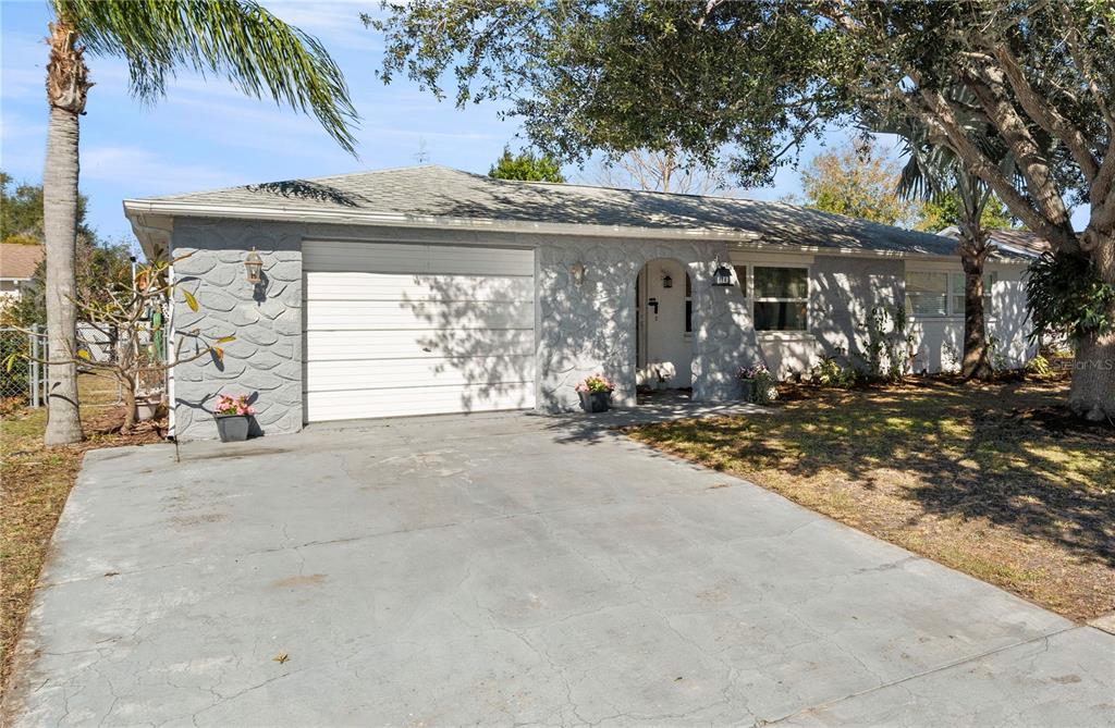 A single-story house with a gray textured facade, a white garage door, and a driveway — 6333 ABERDEEN AVENUE, NEW PORT RICHEY, FL