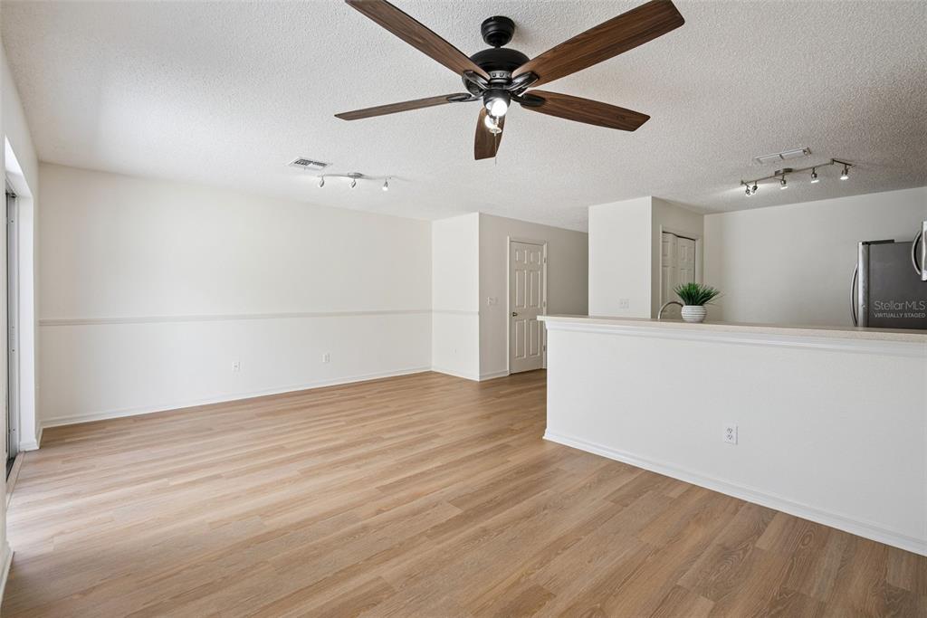An open-concept living area features light wood-look flooring, a ceiling fan, and a kitchen peninsula — 12621 SOMERSET OAKS STREET, ORLANDO, FL