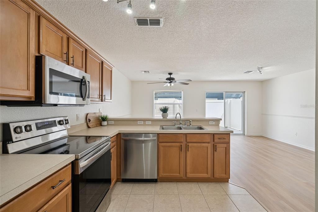 A kitchen features stainless steel appliances, light wood cabinets, and a tile floor — 12621 SOMERSET OAKS STREET, ORLANDO, FL