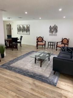A living room with light wood floors, a glass coffee table, and two accent chairs — 4026 TENITA DRIVE, WINTER PARK, FL