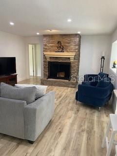 A living room features light wood-look flooring, a stone fireplace, and a gray armchair — 4026 TENITA DRIVE, WINTER PARK, FL