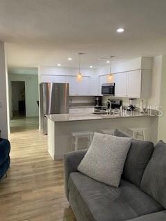 A modern kitchen with white cabinets and stainless steel appliances overlooks a gray sofa — 4026 TENITA DRIVE, WINTER PARK, FL