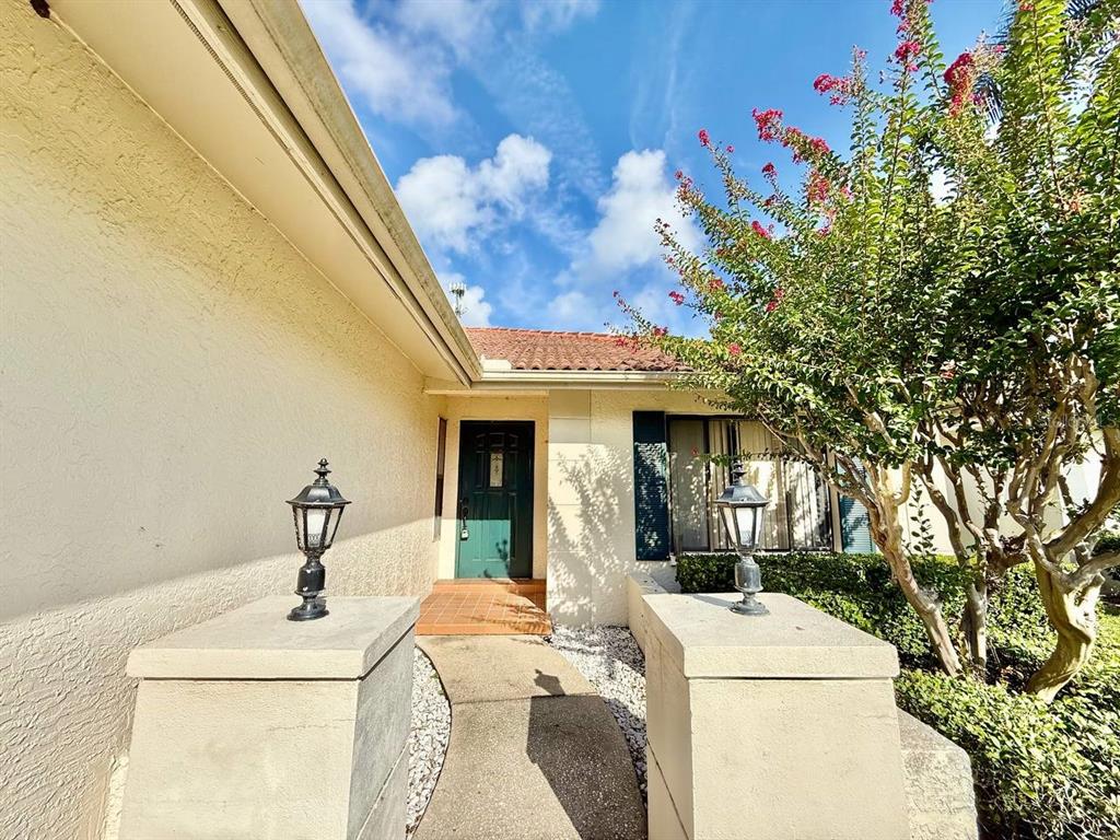 A walkway leads to the front entrance of a house with a green door — 18308 AINTREE COURT, TAMPA, FL