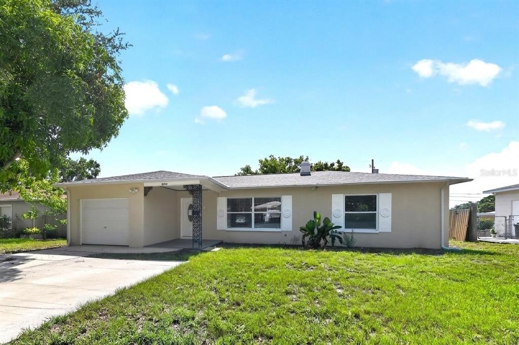 A single-story house with a beige exterior, a one-car garage, and a front lawn — 5235 ROBIN LANE N, ST PETERSBURG, FL