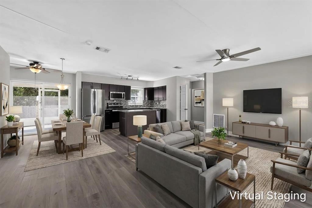 This virtually staged open-concept living and dining area features dark cabinetry and wood-look flooring — 5235 ROBIN LANE N, ST PETERSBURG, FL